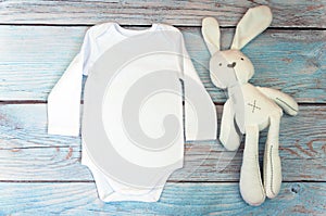 Top view white baby bodysuit with long sleeve on wooden background. Copy space for lettering or your text. Flat lay mockup. Stock