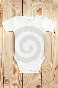 Top view white baby romper bodysuit on wood. Copy space for lettering or your text. Flat lay mockup