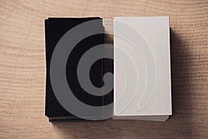 top view of white and black empty business cards stacked on wooden surface.