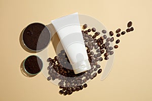 Top view of white bottle container cream, lotion or mask displayed on coffee beans and grounds on beige background. Concept for