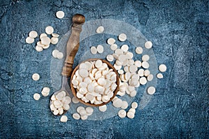 Top view of white chocolate drops or morsels in wooden bowl and spoon