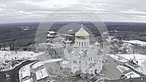 Top view of white church with golden domes in winter. Clip. Beautiful landscape of church on mountain on background of