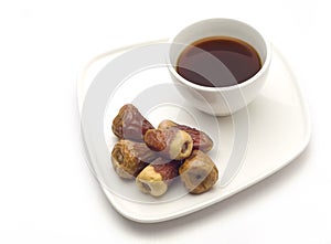 Top view of white coffee cup with dates in a plate.