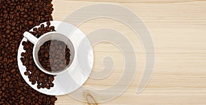 Top view of white coffee cup and roasted coffee beans on wooden background with copy space