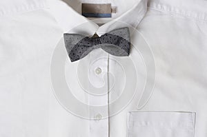 Top view of white cotton shirt for man and grey bow tie.Classic clothing pieces