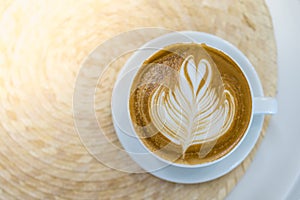 Top view of white cup of hot coffee latte with milk foam heart shape art on round table and copy space