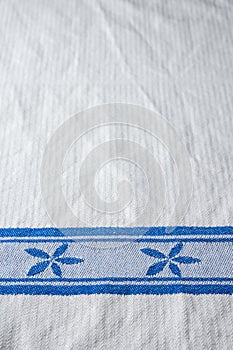 Top view of white dishcloth with blue motifs, as background