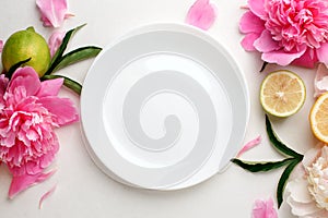 Top view of white empty plate over spring flowers. Flat lay, spring summer season holiday, femenine wedding table setting,