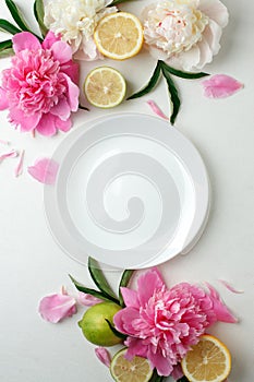 Top view of white empty plate over spring flowers. Flat lay, spring summer season holiday, femenine wedding table setting,