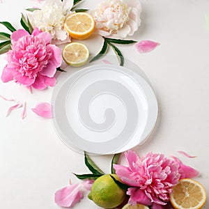 Top view of white empty plate over spring flowers. Flat lay, spring summer season holiday, femenine wedding table setting,