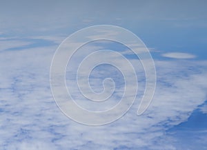 Top view of white fluffy feathery clouds against a blue sky. Abstract sky background. Low depth of field