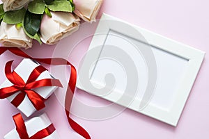 Top view of white frame with copy space , roses and gift boxes on pink background. Sweet Valentine or romance love theme