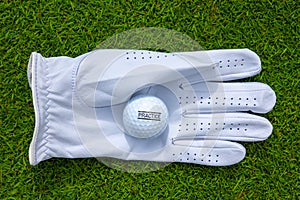 Top view of a white golf glove with a golf ball on a  grassy field