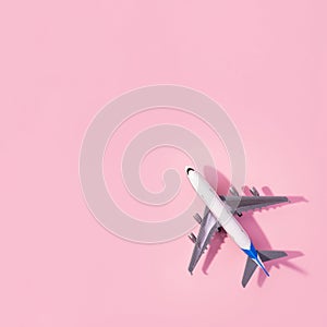 Top view of white model plane, airplane toy on isolated pink background. Flat lay with copy space. Trip or travel banner
