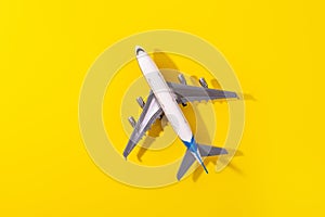 Top view of white model plane, airplane toy on isolated yellow background. Flat lay with copy space. Trip or travel banner