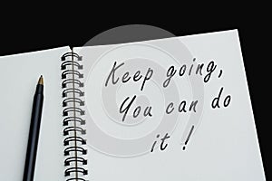 Top view of white notebook with motivational quote on dark background