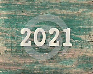 Top view of a white number 2021 as a symbol of the coming New Year. Happy New Year Holiday concept on a rustic wooden background.