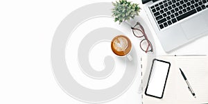 Top view, White Office desk with laptop computer, Blank screen smart phone, cup of coffee, pen and notebook, copy space, Mock up