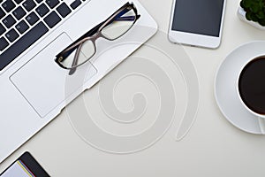 Top view of white office with the frame of laptop, glasses, sma