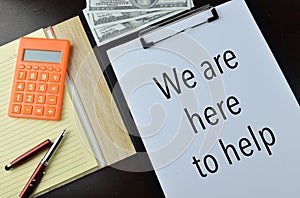 Top view of white paper written with WE ARE HERE TO HELP