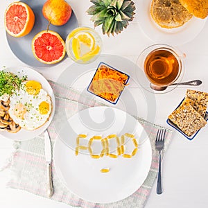 Top view white plate with Food word lettering by vitamin pills on the served wooden table with breakfast meal. Pill instead of foo