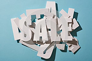 Top view of white sale lettering on pile of letters on blue background.