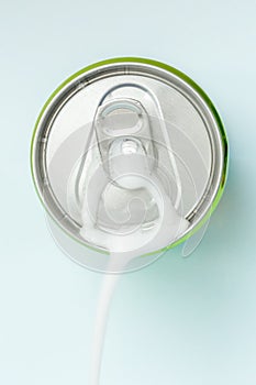 Top view of white soda foam splashing over the aluminum beverage