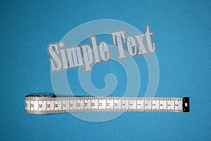 Top view of white soft measuring tape. Minimalist flat lay image of tape measure with metric scale over blue background.