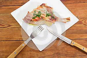 Grilled pork loin on bone on dish, fork and knife