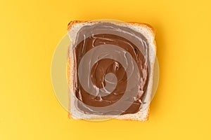 Top view of white toast bread with chocolate hazelnut spread on the yellow background. Morning breakfast concept. Food mockup with