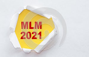 Top view of white  torn paper and text mlm - multilevel marketing on yellow background