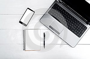 Top view on white wooden table with open blank laptop computer.