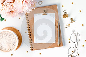 Top view of white working table background with cup of coffee putting on it. Flat lay glasses, flower, golden paper binder clips,