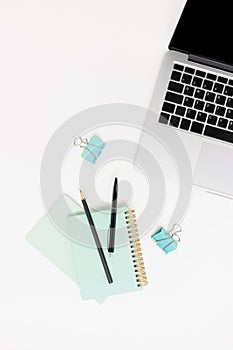 Top view of white workspace with laptop and stationery