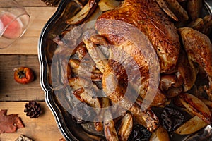 Top view of whole baked turkey stuffed with apples served with potato on the black round dish. Wooden background with autumn