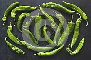 Top view of whole green peppers on dark background
