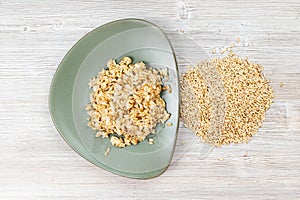 Top view of whole oat grains and boiled porridge