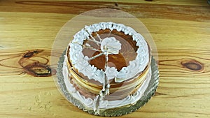 Top view at whole round caramel cake decorated with white cream divided into parts