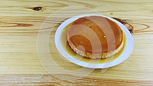 Top view on whole round soft flan with caramel syrup on white round plate