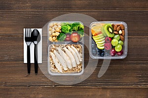 Wholesome nutrient rich food set in take away boxes with spoon and fork on wood table ready to eat