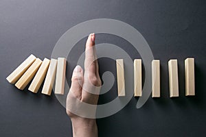 Top view whomen hand stopping falling dominos in a business crisis management conceptual image