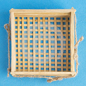 Top view of wicker basket isolated on blue background. Empty handmade wooden bowl.