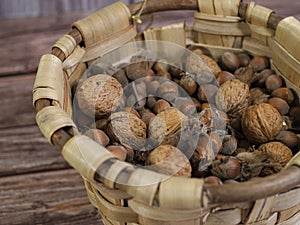 top view of wicker basket with nuts: walnuts and hazelnuts. wooden background