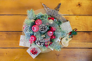 Top view of wicker sleigh filled with holiday decor, pine cones, pine sprigs, apples and gifts, rustic old fashioned wooden