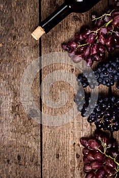 Top view Wine Background Wine Bottles Black and Pink Ripe Grapes on Wooden Background Vertical Copy Space