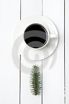 Top view of winter composition of cup of coffee and fir tree branch on white wood background. Christmas morning in Scandinavian