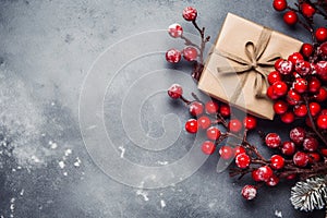 Top view of a winter composition of gift box kraft and juicy red rowan berries, on a textured gray background. Christmas copyspace