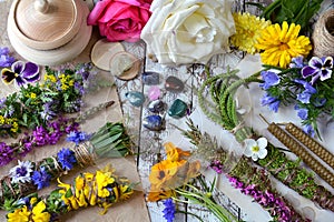 Top view of witchery scrolls with magic herbs, summer flowers and crystals on table