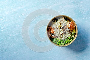 Top view of wok box, bowl of rice on black background. Rice fried and stirred with salmon, avocado, onion, mushrooms, broccoli