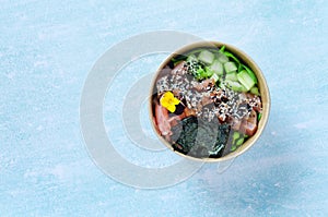 Top view of wok box, bowl of rice on black background. Rice fried and stirred with salmon, avocado, onion, mushrooms, broccoli